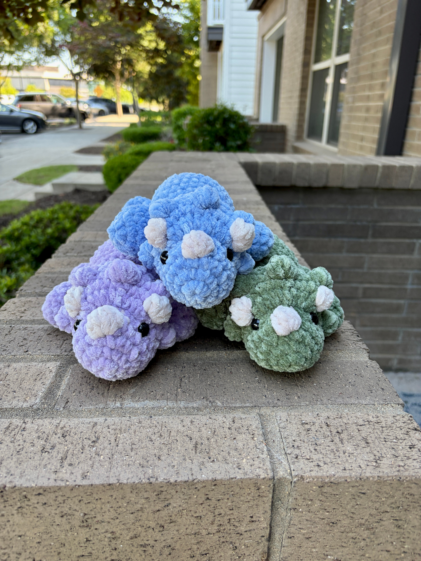 Trio of purple, blue, and green crochet triceratops plushies